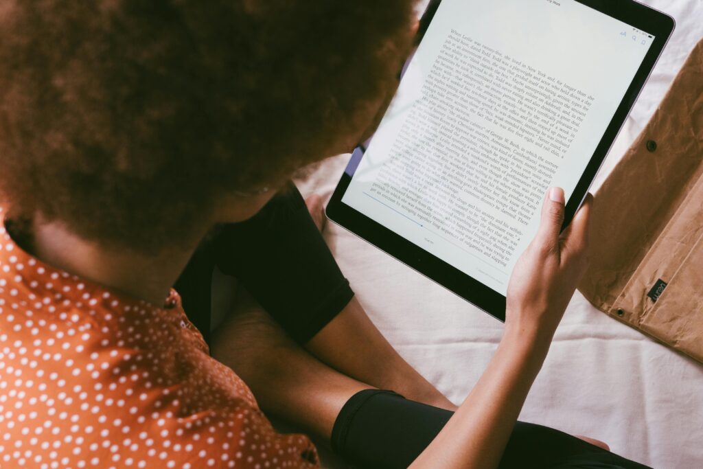 How to Write and Publish a Book Using AI (Full Step‑by‑Step Guide) Woman reading an ebook on a tablet indoors, relaxed modern lifestyle.