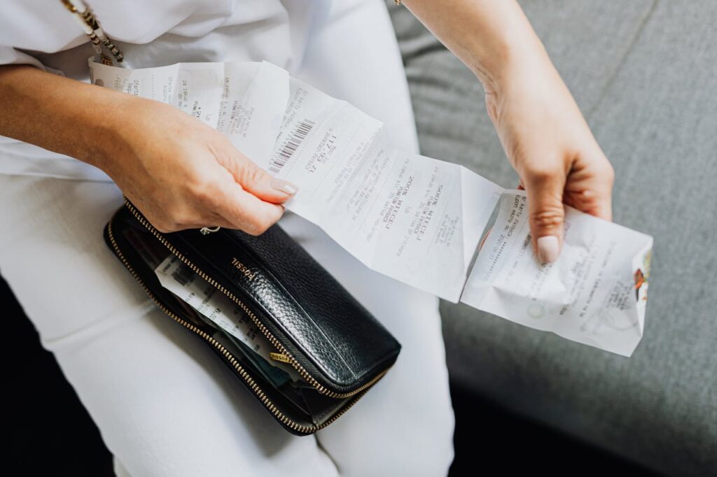 Money Myths Young Adults Should Stop Believing Close-up of a woman's hands managing multiple receipts taken from a black wallet.